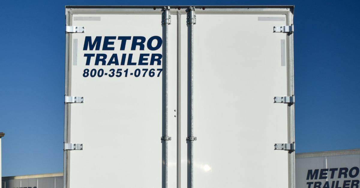 The rear doors of a white Metro Trailer semi-trailer with company branding, hardware, lights, and reflectors.